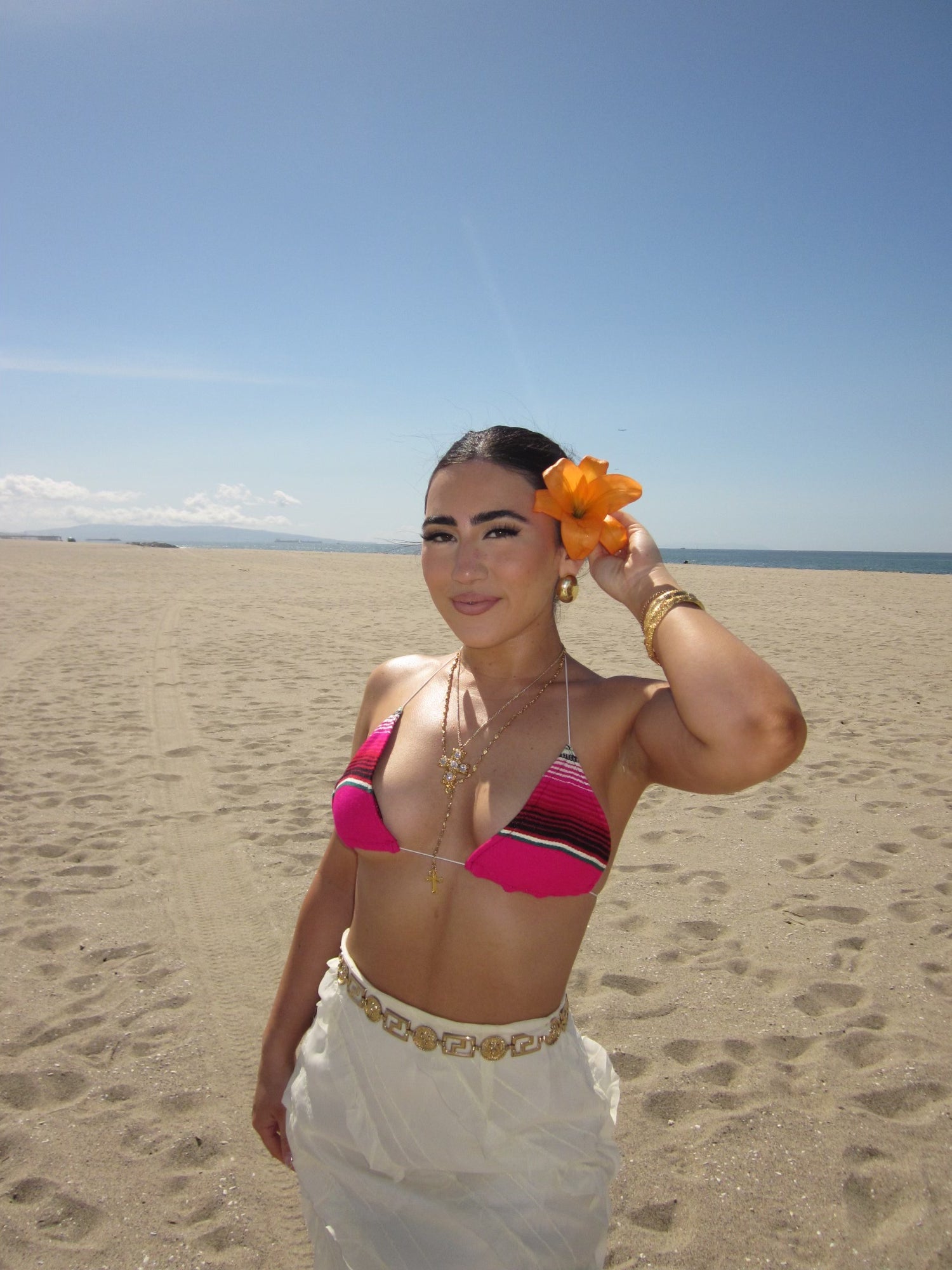 model at beach holding flower in her hair wearing la rosa top 
